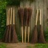 Several brooms are leaning against a wooden fence in an outdoor setting. Anteprima dell’immagine prodotto