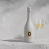 A bottle of white wine and two glasses of wine are displayed on a stone surface against a textured gray background. Produktbild-Vorschau