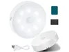 A white, circular LED light with a motion sensor is shown, along with a charging cable and two color swatches (teal and black). Another part of the light is shown at an angle in the foreground. Produktbild-Vorschau