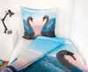 A bed with swan-themed bedding, a bedside table with a lamp and clock. Podgląd zdjęcia produktu