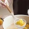 A person is using a white ladle with a wooden handle to scoop corn from a pot of soup. Náhled obrázku produktu