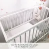 A white crib with a white sheet and a gray pillow with a stuffed animal on it. Produktbild-Vorschau