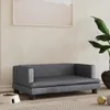 A dark gray dog bed is placed on a rug in a room with a plant and a framed picture on the wall. Podgląd zdjęcia produktu