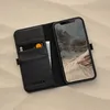 A black leather iPhone case with card slots is shown open, displaying an iPhone with a mountain landscape wallpaper. Produktbild-Vorschau