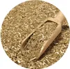 A close-up view of dried yerba mate leaves and stems in a wooden scoop, with more leaves filling the background. Podgląd zdjęcia produktu