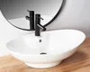 A white vessel sink with a black faucet is shown on a wooden countertop, with a mirror in the background. Náhled obrázku produktu