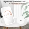 A white makeup mirror with LED lighting is placed on a small white table, with a plant in the background. The mirror displays a graphic indicating 10 hours of battery life. Produktbild-Vorschau