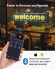 A person is holding a smartphone in front of a window with a digital LED sign displaying "welcome" in the background. People are visible inside the establishment behind the window. Produktbild-Vorschau