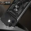 A black phone case with a ring stand and camera cover is shown in a dynamic, angled shot, appearing to be dropped onto a surface that is cracking. Produktbild-Vorschau
