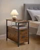 A bedside table with a lamp and books next to a bed. Náhled obrázku produktu