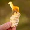 A hand holding a burning fire starter made of wood shavings. Podgląd zdjęcia produktu