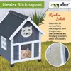 A cat house with a cat sleeping inside, set against a grassy background with some plants. Produktbild-Vorschau