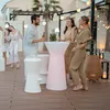 People enjoying a party outdoors with a lighted table and stools. Produktbild-Vorschau