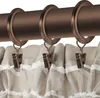 Close-up of curtain rings and clips attached to a curtain rod, with the top of a curtain visible. Produktbild-Vorschau
