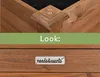 A close-up view of a wooden planter box, showing construction details and a brand logo. Produktbild-Vorschau