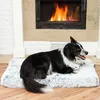 A dog is lying on a fluffy dog bed in front of a fireplace. Produktbild-Vorschau