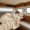 A person sleeping under a blanket in a camper or RV. Náhled obrázku produktu