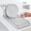 A hand is placing a glass into a dish drying rack on a countertop. Podgląd zdjęcia produktu