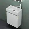 A white bathroom vanity with a sink and faucet against a textured green wall and dark tiled floor. Produktbild-Vorschau