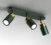 A three-headed ceiling light fixture with green cylindrical lamps and gold accents, mounted on a green rectangular base. Produktbild-Vorschau