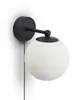 A black wall lamp with a white glass globe shade and a pull chain, mounted on a white wall. Podgląd zdjęcia produktu
