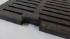 A close-up view of a cast iron grate with a protruding tab. Voir les images du produit