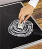 A hand is shown cleaning a glass ceramic stovetop with a special scraper and cleaning paste. Náhľad obrázku produktu