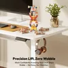 A white standing desk with a computer monitor, keyboard, mouse, and decorative stacking figures. Headphones are hanging from the side of the desk. Produktbild-Vorschau