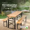 A wooden beer garden table and two benches set up on a wooden deck outdoors, with a blurred background of a garden. Produktbild-Vorschau