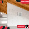 An interior shot of a room under construction with wooden beams and white brick walls. A small white maintenance door is mounted on the wall. Produktbild-Vorschau