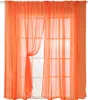 Two sheer orange curtains are hung over a window with multiple panes. One curtain is tied back with a fabric tie. Produktbild-Vorschau