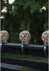 Three solar-powered globe lights are attached to a dark railing, with trees in the background. Produktbild-Vorschau