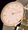 A close-up view of a women's watch face with a rose gold-colored case and hands, and a light pink dial. The watch has a gray leather strap. Produktbild-Vorschau