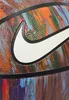 A close-up of a basketball with a colorful, abstract design and a white Nike swoosh logo. Produktbild-Vorschau
