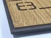 Close-up of a wooden clock face with carved numbers and a dark gray border. Produktbild-Vorschau