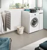 A laundry room scene with a washing machine, drying rack, and laundry basket. Produktbild-Vorschau