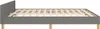 A side view of a grey fabric bed frame with a wooden slatted base and wooden legs, set against a white background. Náhled obrázku produktu