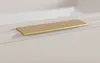 A close-up shot of a gold cabinet handle on a white cabinet. Produktbild-Vorschau