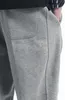 A close-up shot of grey sweatpants, showing the pocket detail and seam. Produktbild-Vorschau