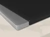 A close-up view of the corner of a black induction hob with a silver frame, resting on a light-colored countertop. Anteprima dell’immagine prodotto