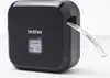 A black Brother P-Touch Cube Plus label maker with a label tape emerging from the side. Náhled obrázku produktu