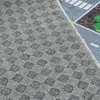 A close-up view of a rug with a checkered pattern and a street scene. Produktbild-Vorschau