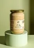 A jar of mustard sits on a light green pedestal against a light green background. Produktbild-Vorschau