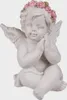 A white cherub figurine with a pink rose wreath on its head sits with its hands clasped. Produktbild-Vorschau