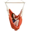 A woman is sitting in an orange hammock chair against a white background. Podgląd zdjęcia produktu