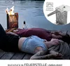 Two people lying on a wooden deck by a lake with a fire pit burning. Produktbild-Vorschau