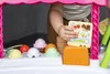 A child's hand is interacting with a toy ice cream cart, placing a menu card. Anteprima dell’immagine prodotto