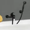 A black bathtub faucet and showerhead are mounted on a gray wall above a white bathtub. Produktbild-Vorschau