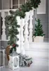 Christmas decorations on a porch, including a garland, a small tree, and a lantern. Náhled obrázku produktu