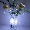 A string of white LED lights is wrapped around a glass vase containing artificial flowers and greenery. Produktbild-Vorschau